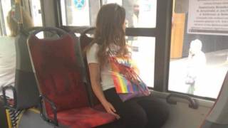 Dziewczyna w autobusie tęczową torebką na kolanach, która została skrytykowana przez